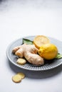 Sliced ginger root and lemon on a ceramic plate on a light textured background Royalty Free Stock Photo